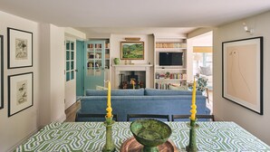 A living room with a sofa, a fireplace, a television, and bookshelves. - Bridlepath Cottage - Luxury Cottages (Hungerford)