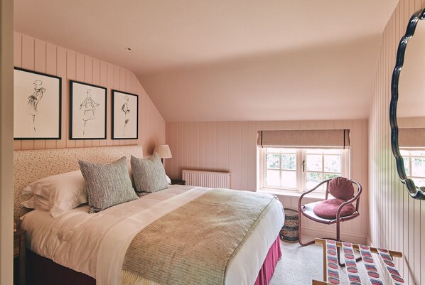 Une chambre à coucher avec un lit, une chaise, une fenêtre et des œuvres d’art murales.