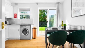 Eine moderne Küche mit weißen Schränken, einer Waschmaschine und einem Essbereich mit Tisch und Stühlen.