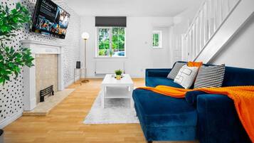 A modern living room with a blue sofa, white coffee table, and a fireplace.