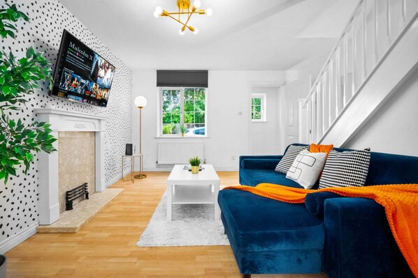 A modern living room with a blue sofa, white coffee table, and a fireplace.