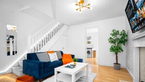 Ein modernes Wohnzimmer mit einem blauen Sofa, einem weißen Couchtisch und einer Treppe.