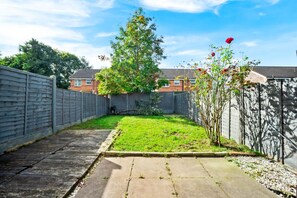 A residential backyard with a lawn, a tree, and a wooden fence.