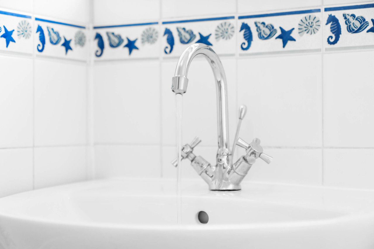 A bathroom sink with a modern faucet and a decorative tile border.