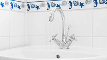 A bathroom sink with a modern faucet and a decorative tile border.