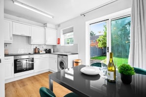A modern kitchen with white cabinets, a built-in oven, and a washing machine.