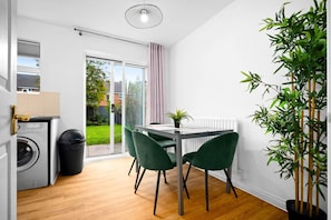 A compact living space with a dining area, a washing machine, and a large window.