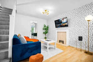 A modern living room with a blue sofa, white coffee table, and a fireplace.