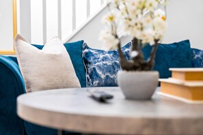 A round table with a remote control, a white bowl, and a potted plant with white flowers. - Stylish Two Bed House - Garden - Parking - WIFI (West Midlands)