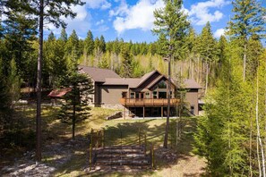 A modern two-story cabin surrounded by a dense forest. - The Haskill Highland Retreat (Whitefish)
