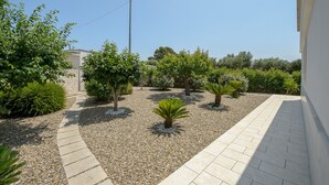 Un jardín ajardinado con diferentes arbustos y un sendero pavimentado.