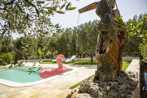 A swimming pool with a flamingo float, surrounded by a stone wall and trees. - ancient villa converted into a luxury residence by pugliadamare (Martina Franca)