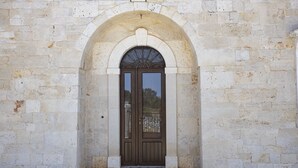 A stone building with a central arched doorway, a small step leading up to the entrance, and a metal gate. - ancient villa converted into a luxury residence by pugliadamare (Martina Franca)