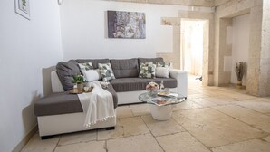A living room with a grey sofa, white cushions, a glass coffee table, and a painting on the wall. - ancient villa converted into a luxury residence by pugliadamare (Martina Franca)