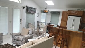 Una sala de estar con sofá, sillas, una mesa de comedor y una zona de cocina con refrigerador.