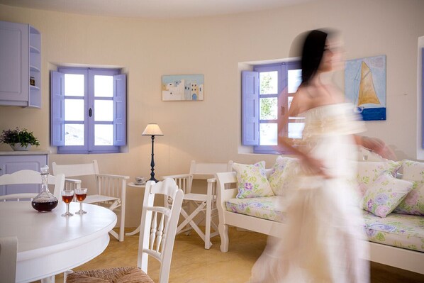 Une pièce avec un canapé blanc, une table à manger avec des chaises, une lampe et un tableau au mur.