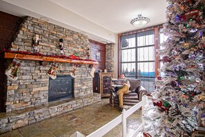 Cozy living room with a fireplace, comfortable sofa, and large window offering a view of the outdoors.