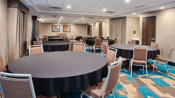 A conference room with round tables and chairs, a carpeted floor, and a door in the background.