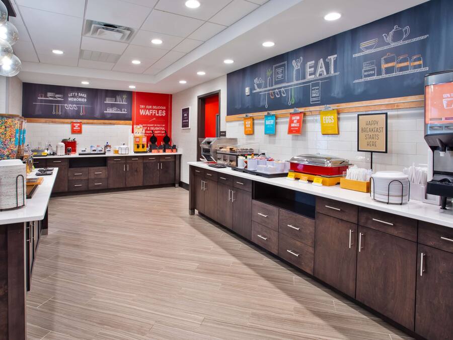 A modern kitchen area with a counter, cabinets, and a coffee machine.