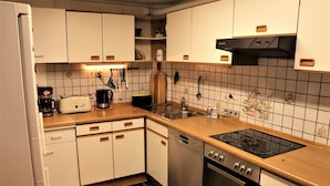 Une cuisine avec des meubles blancs, une cuisinière noire et un lave-vaisselle.