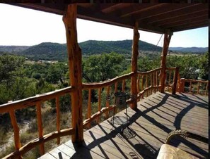 Une terrasse en bois dotée d’une balustrade, qui offre une vue sur un paysage montagneux.