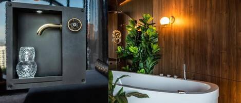 Un baño moderno con una bañera independiente, un tocador con espejo, y una pared decorativa con plantas e iluminación.