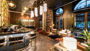 Un bar moderno con un camarero, taburetes de bar y una zona de estar con sofás y una mesa de centro.