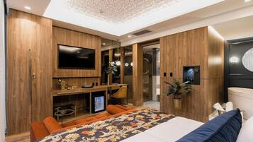 A modern bedroom with a large bed, a TV, and built-in wardrobes.