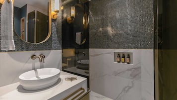 A modern bathroom with a white sink, gold fixtures, and a mirror.