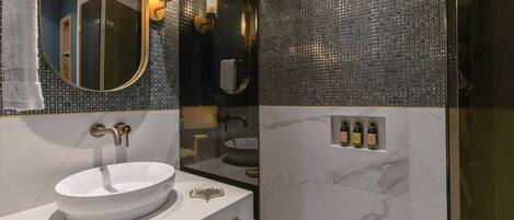 A modern bathroom with a white sink, gold fixtures, and a mirror.