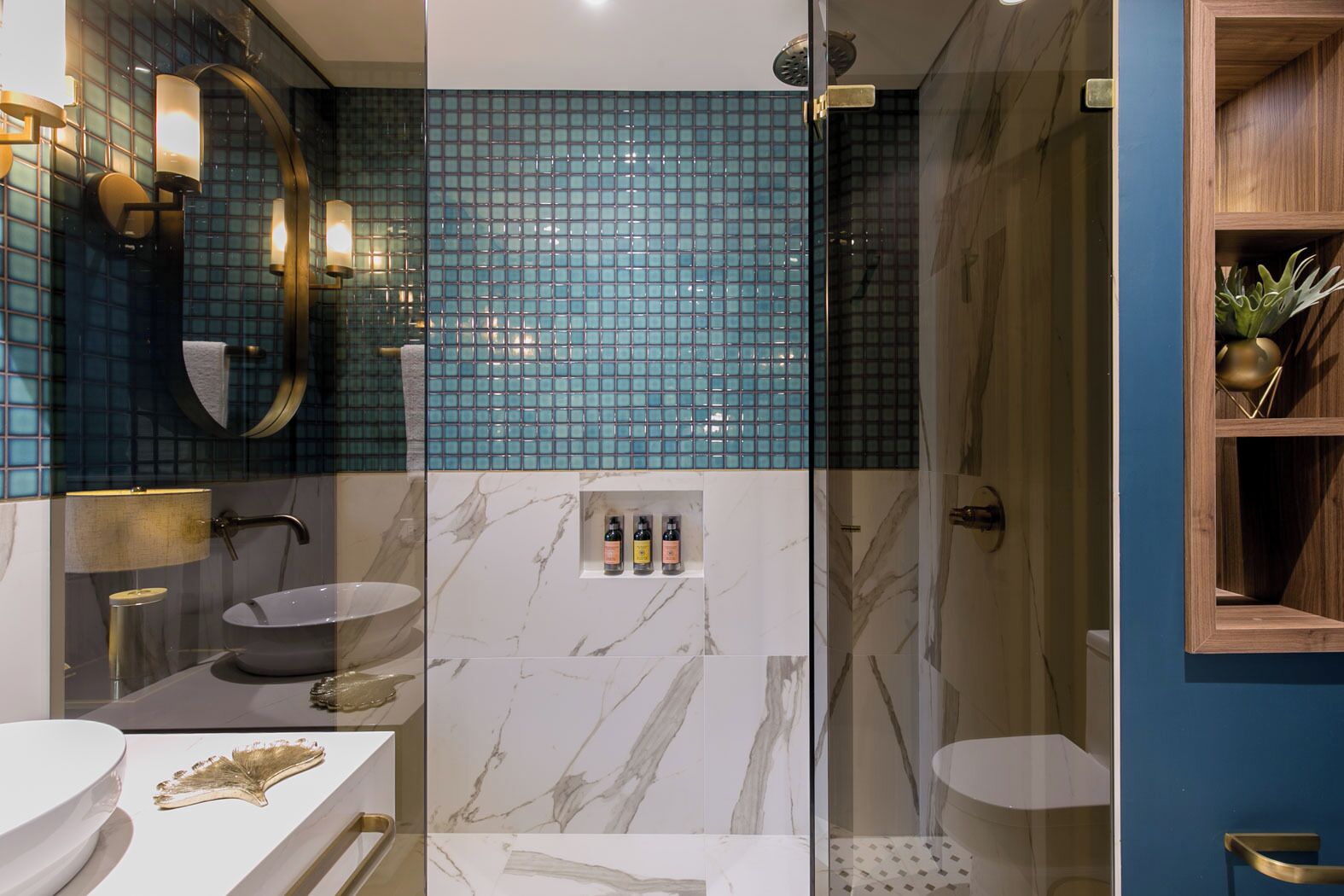 A modern bathroom with a glass shower enclosure, a marble vanity, and a blue-tiled shower wall.