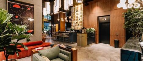 A modern lobby with a bar area, seating, and a reception desk.