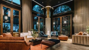 Un amplio salón con sofás de cuero, una mesa de centro y un ventanal con vistas a árboles.