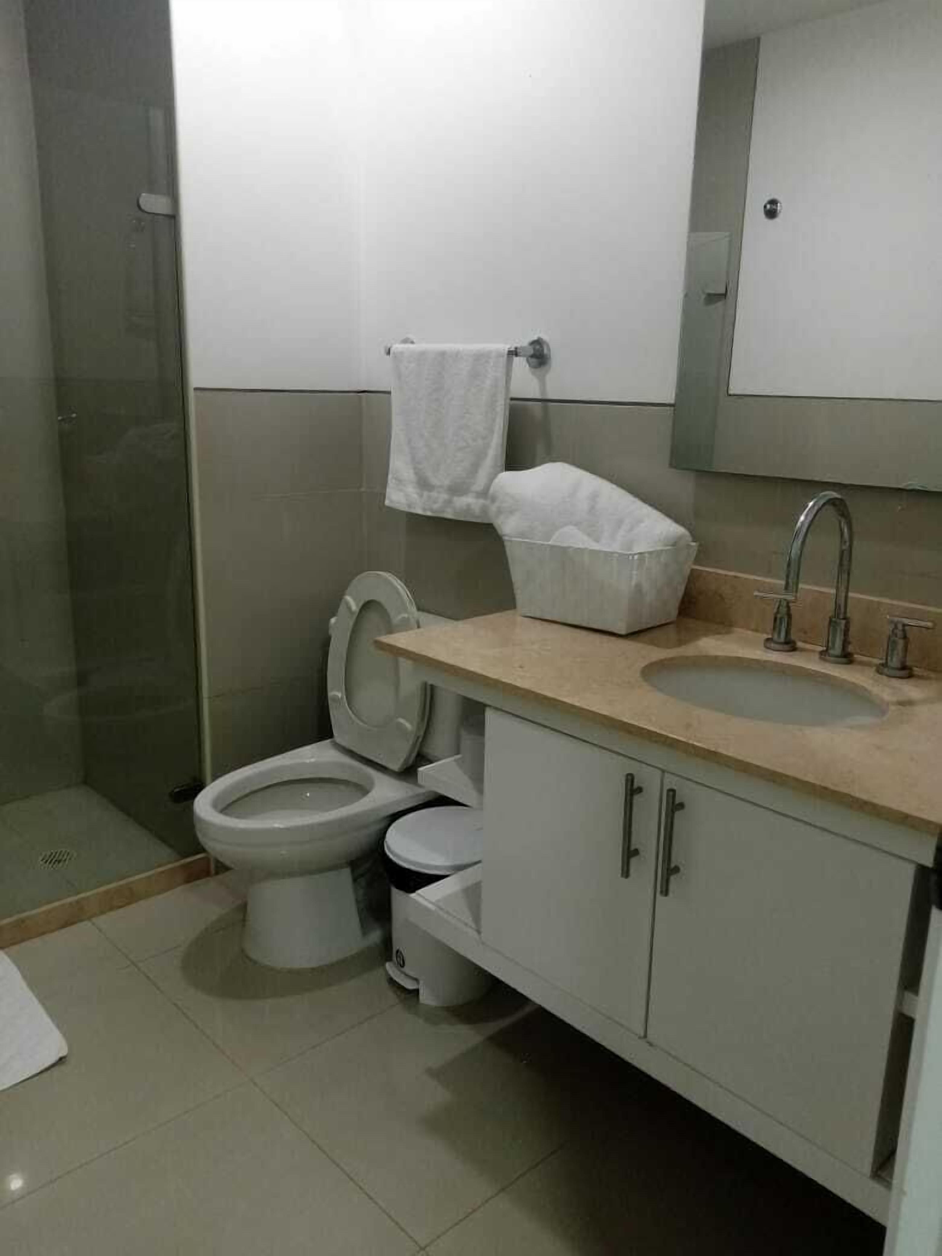 Une salle de bain comprenant des toilettes, un bidet, un lavabo et une douche à parois de verre.
