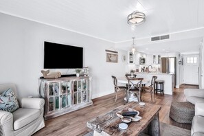 A modern living room with a wooden coffee table, white sofas, and a television mounted on the wall.
