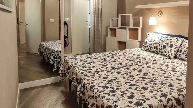 Een slaapkamer met een bed, nachtkastje, spiegel en kledingkast.
