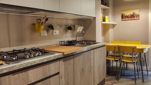 Een moderne keuken met een centraal eiland, houten kastjes en een eethoek met gele stoelen.