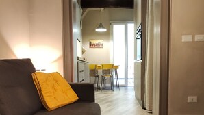 Een moderne woonkamer met een bank, een eettafel met stoelen en een keuken in de achtergrond.