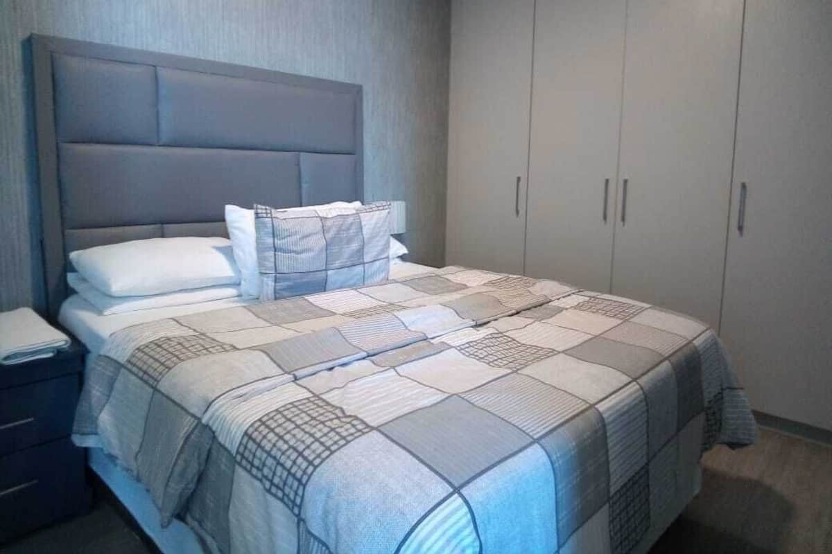 A bedroom with a bed, pillows, a nightstand, and a wardrobe.