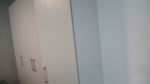 A room with a large white wardrobe, a small table, and a chair. - Rose Of Rose (Johannesburg)