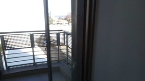 A balcony with a metal railing and a view of a building in the distance. - Rose Of Rose (Johannesburg)