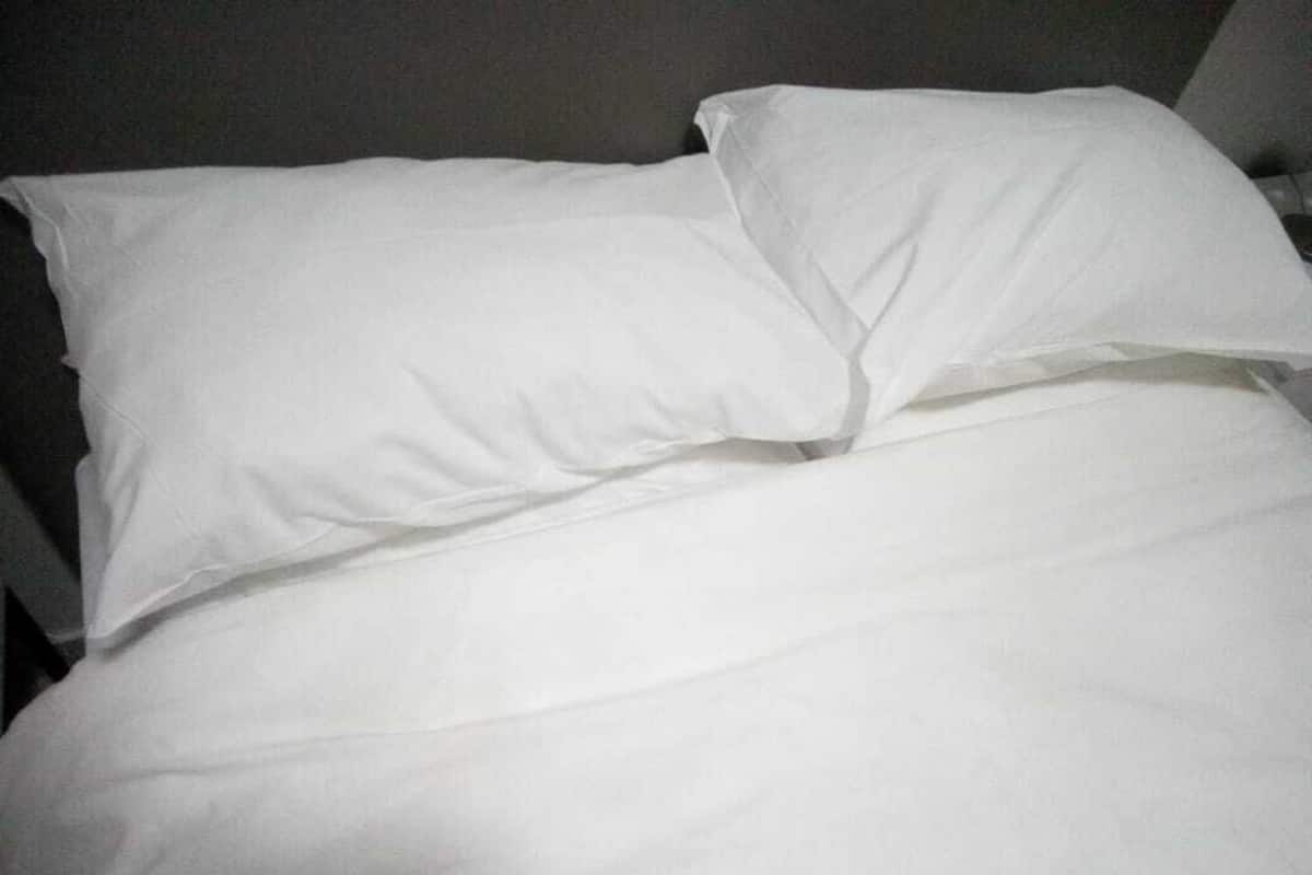A bed with white bedding and pillows.