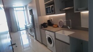 A modern kitchen with a washing machine, microwave, and sink. - Rose Of Rose (Johannesburg)