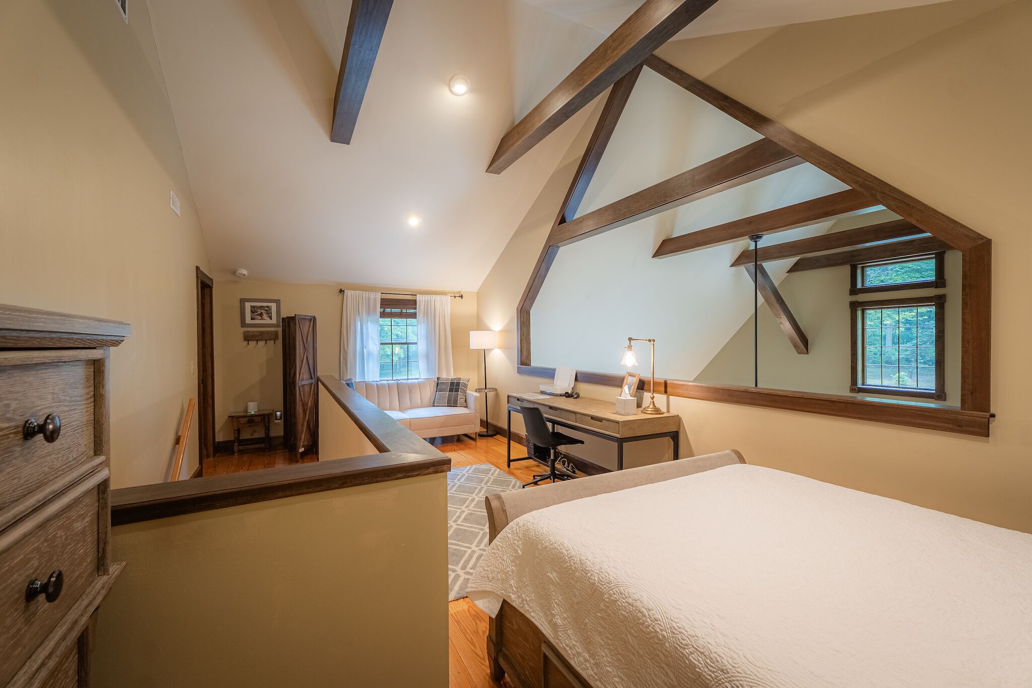 Une chambre avec un plafond de style industriel, un lit, un bureau et une fenêtre.