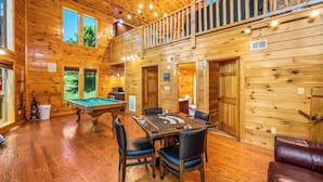 A wooden cabin with a pool table, multiple windows, and a balcony.