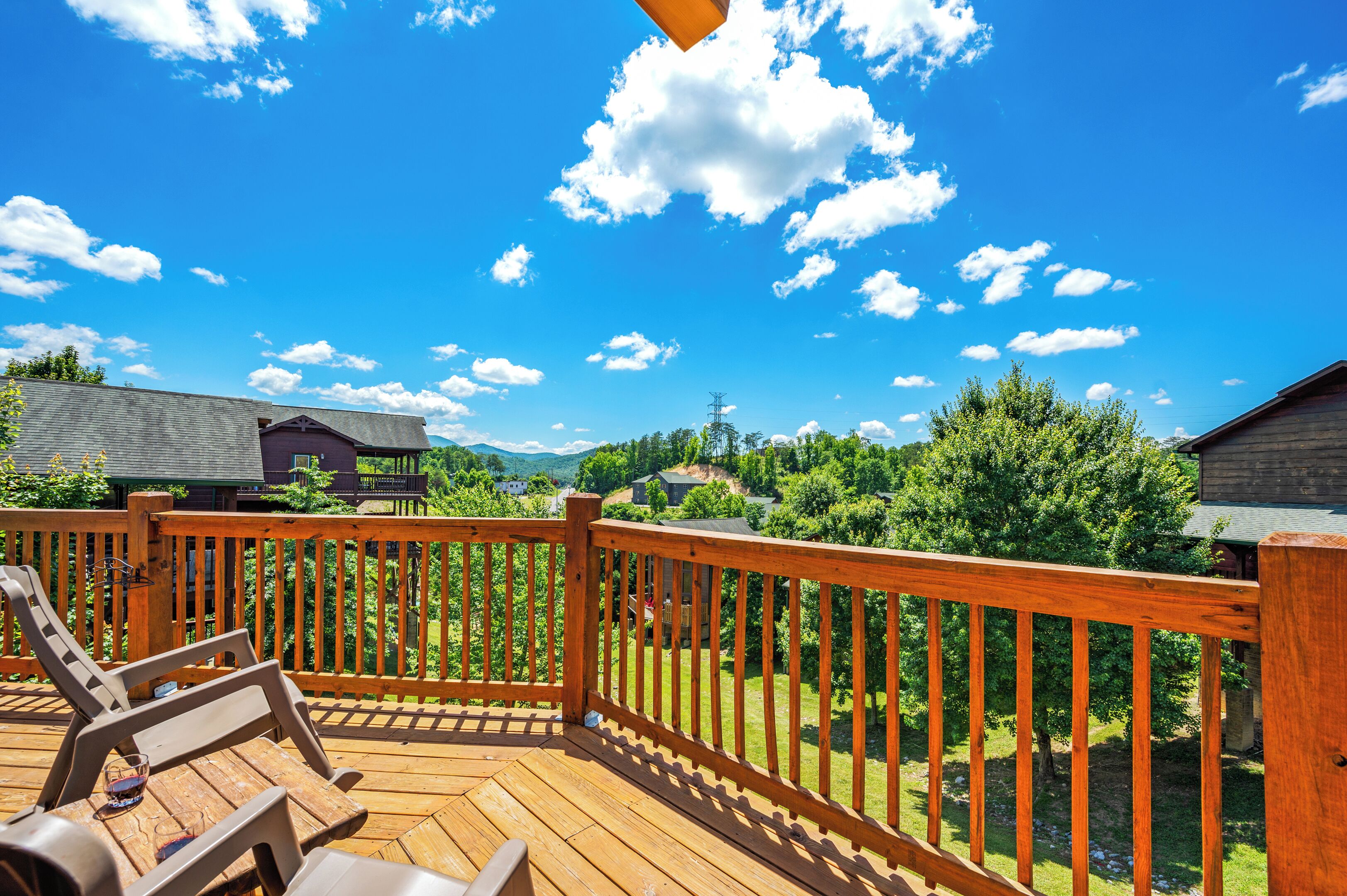 Una terraza de madera con vistas a una zona residencial, que incluye casas y árboles.