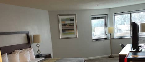 A hotel room with a bed, desk, and computer.