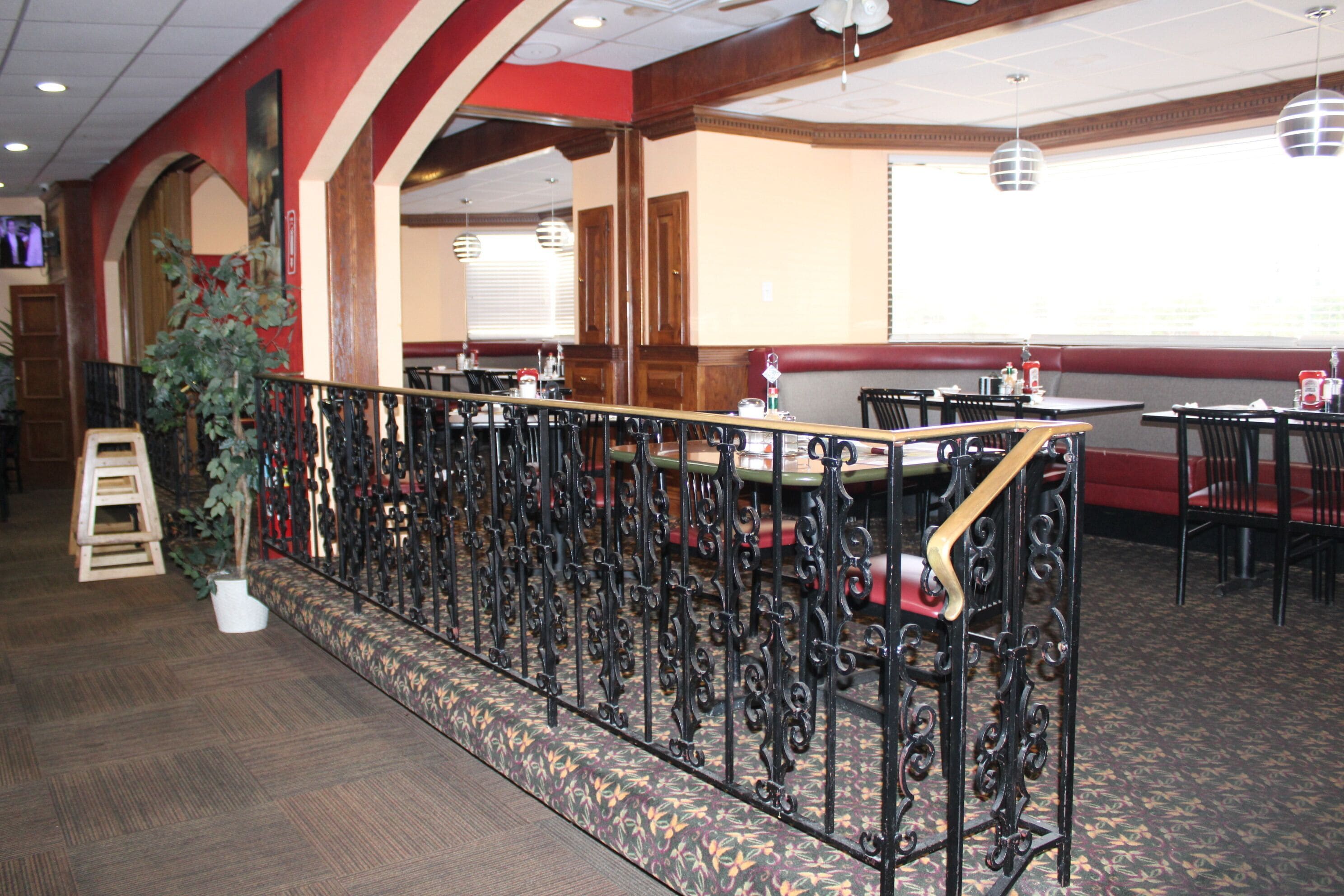 Ein Restaurantinneres mit einer hohen Holztresen, schwarzen Metallgeländern und einem gemusterten Teppich.