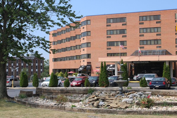 A multi-story hotel with a registration area, parking lot, and a landscaped garden with rocks and shrubs. - APM Inn and Suites (Hagerstown)