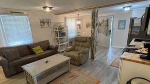 A living room with a sofa, a chair, a coffee table, and a rug. - Pet-Friendly 2BR /2 min Walk to Beach /Pool+Hot Tub/ Golf Cart option (North Myrtle Beach)